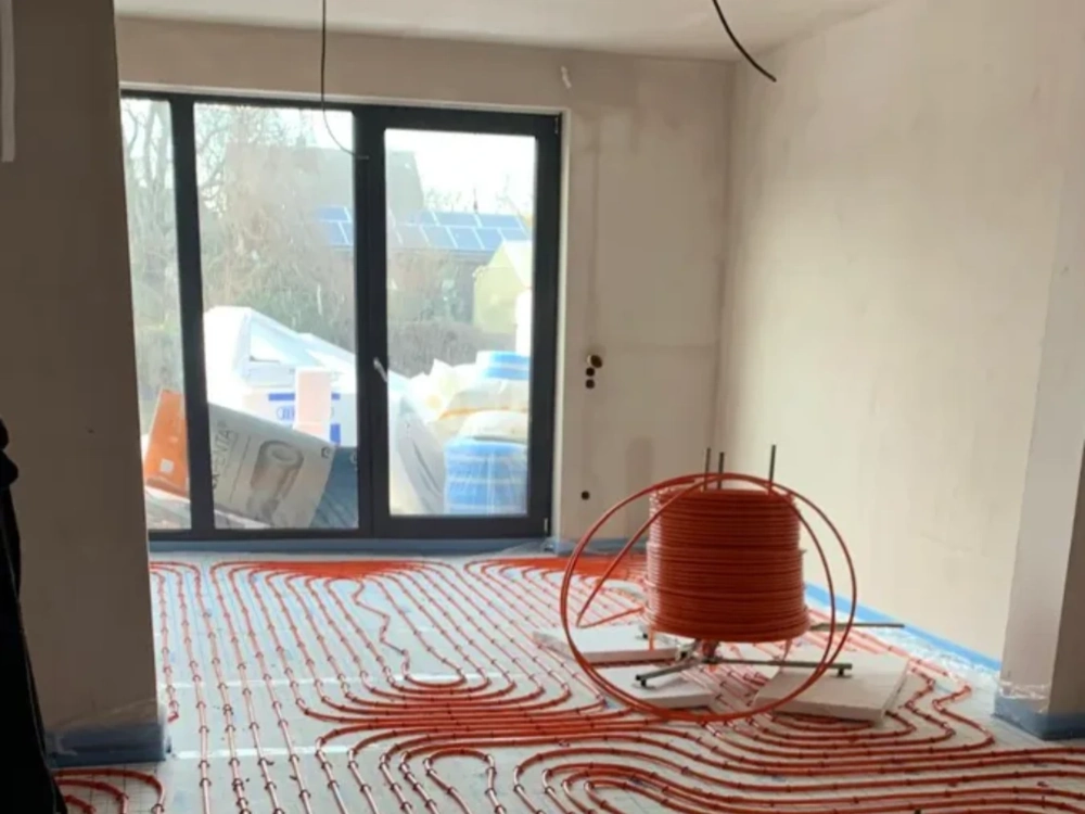 Ogrzewanie podłogowe w trakcie montażu – rozłożone rury i zwinięta spirala w surowym wnętrzu