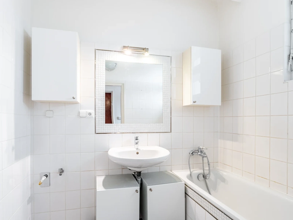 Wyremontowana łazienka z białą ceramiką: umywalka, lustro, szafki i wanna