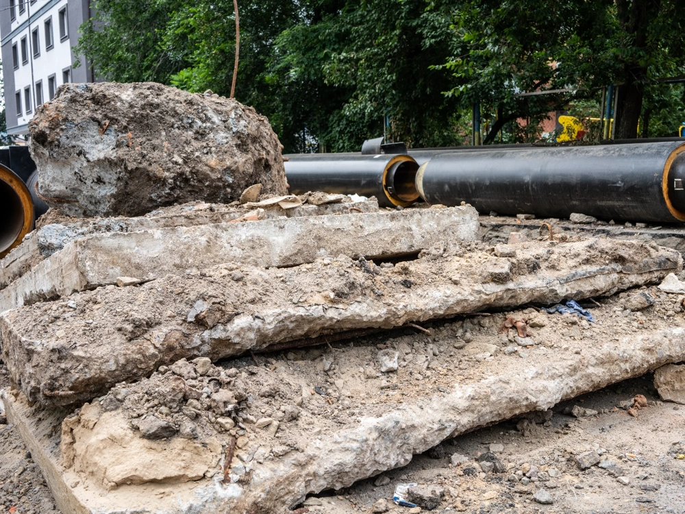 Stosy betonowych płyt i gruzu po wyburzeniach na budowie z widocznymi rurami
