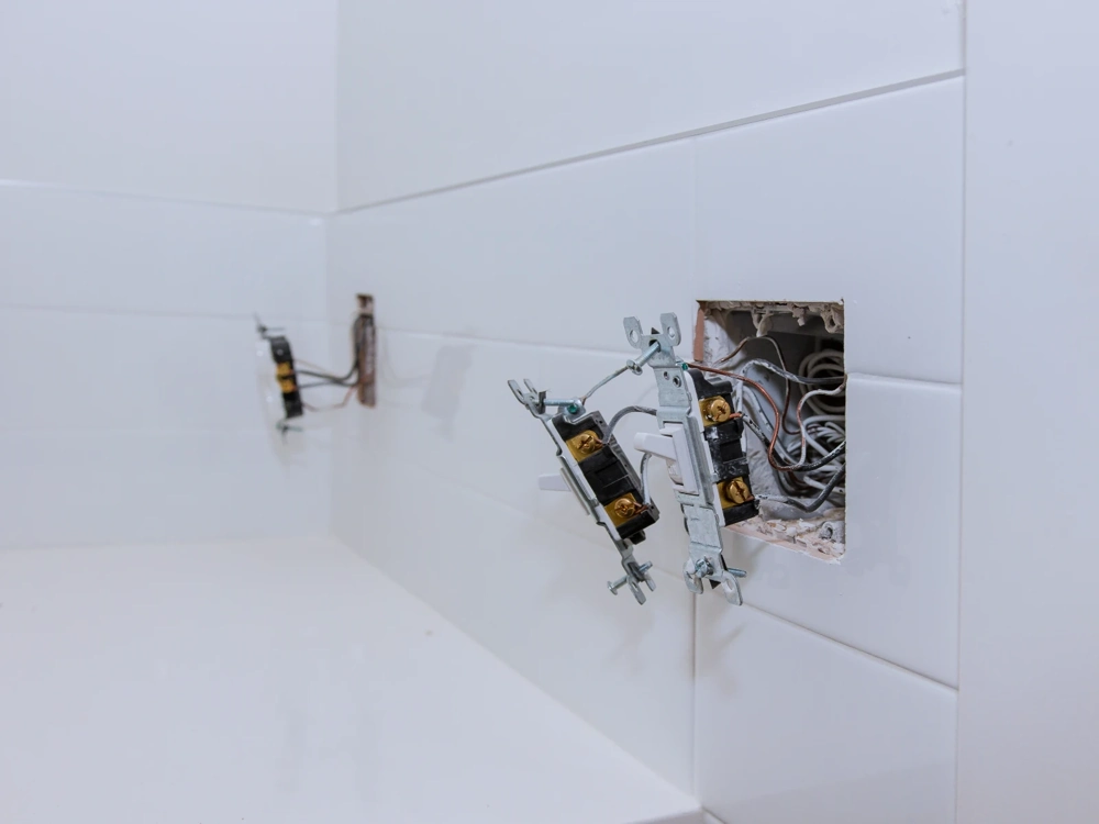 Instalacje elektryczne – odsłonięte puszki i moduły elektryczne z przewodami na białych płytkach